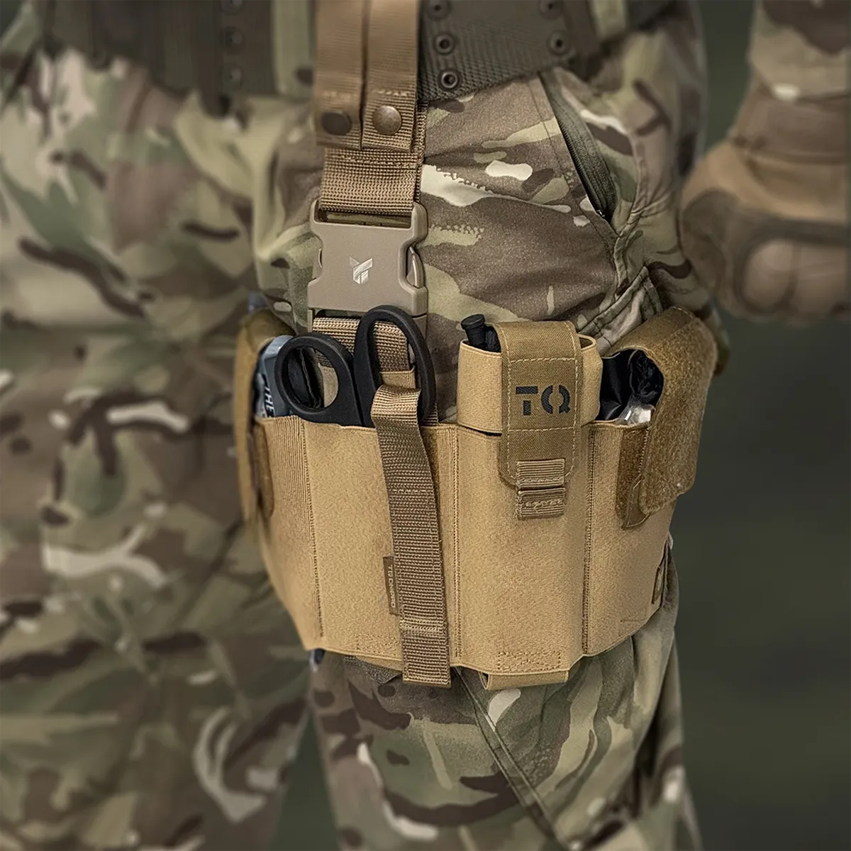 Operatore con cosciale medico aperto DNIPRO PM25 GEN2 Coyote indossato sulla coscia con kit di primo soccorso pronto all'uso.