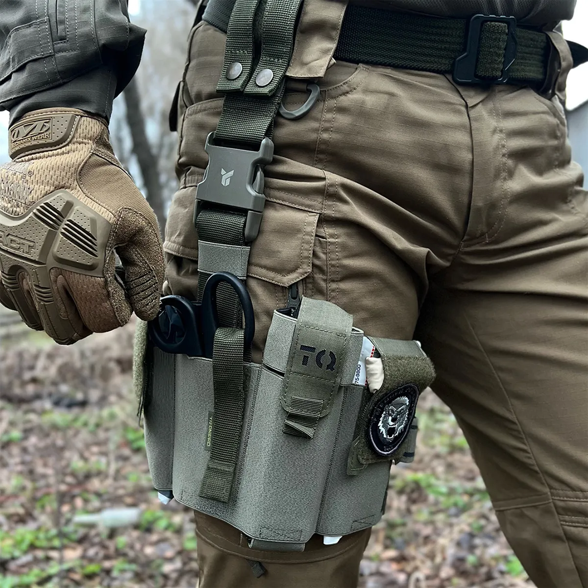 Operatore con cosciale medico aperto DNIPRO PM25 GEN2 Oliva indossato sulla coscia con kit di primo soccorso pronto all'uso.