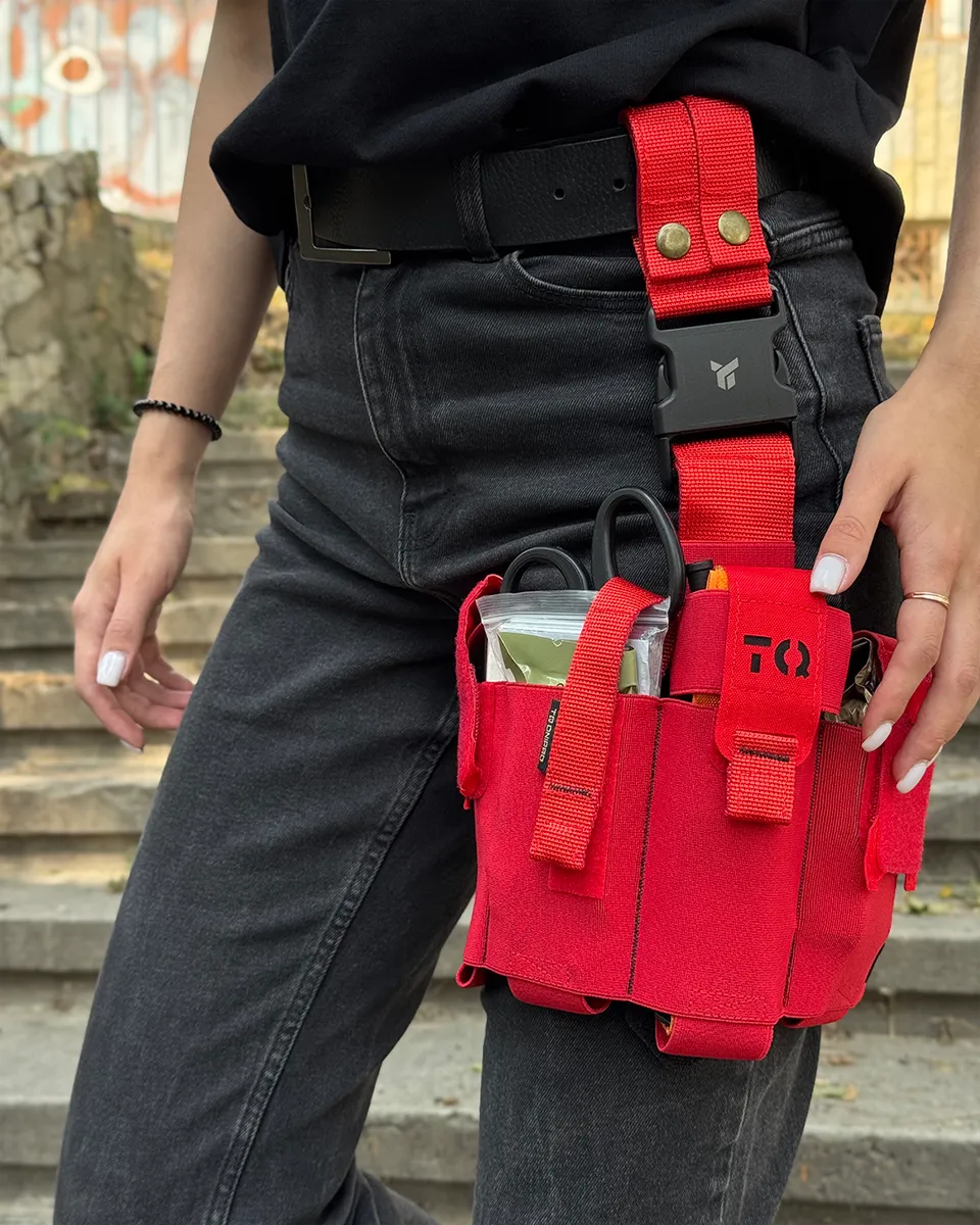 Operatore con cosciale medico aperto DNIPRO PM25 GEN2 Rosso indossato sulla coscia e kit di primo soccorso pronto all'uso.