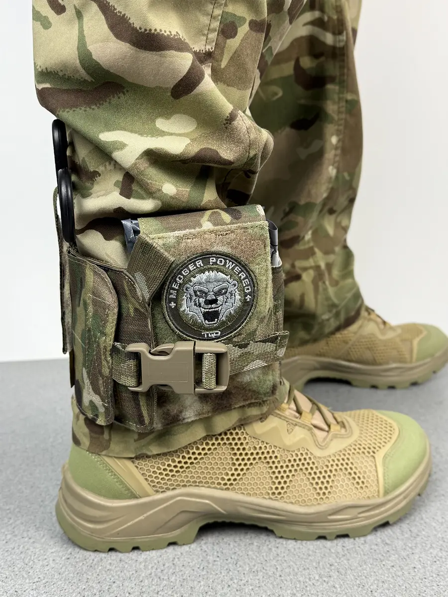 Custodia IFAK da caviglia tattica DNIPRO PM23 in Multicam indossata sopra lo stivale tattico con tasche porta forbici e kit medico facilmente accessibile.