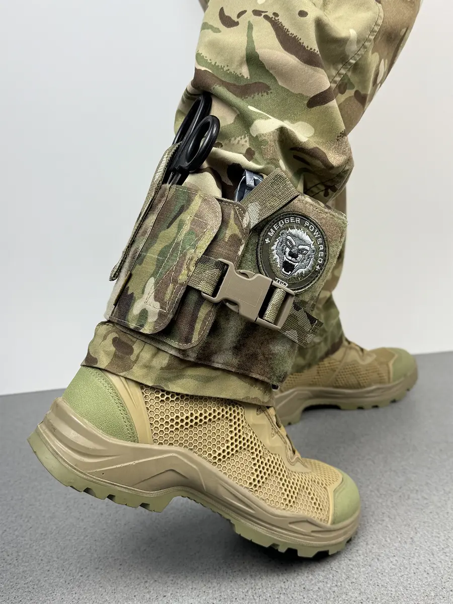 Vista prospettica della custodia IFAK da caviglia tattica DNIPRO PM23 in Multicam indossata, con fissaggio stabile e accesso rapido all'equipaggiamento medico.