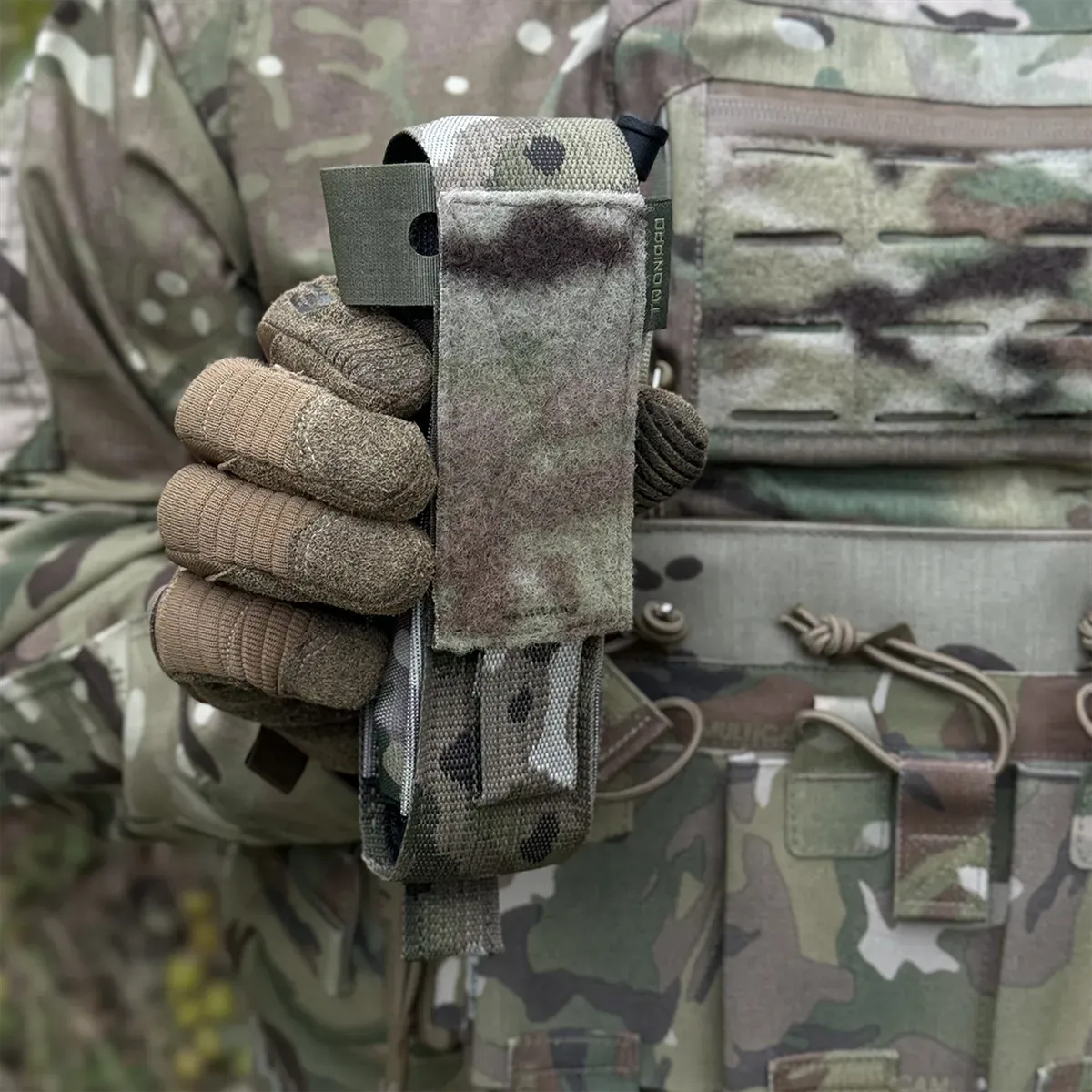 Dettaglio del porta tourniquet tattico DNIPRO PM01 GEN2 Multicam tenuto in mano per evidenziare struttura compatta e chiusura a Velcro