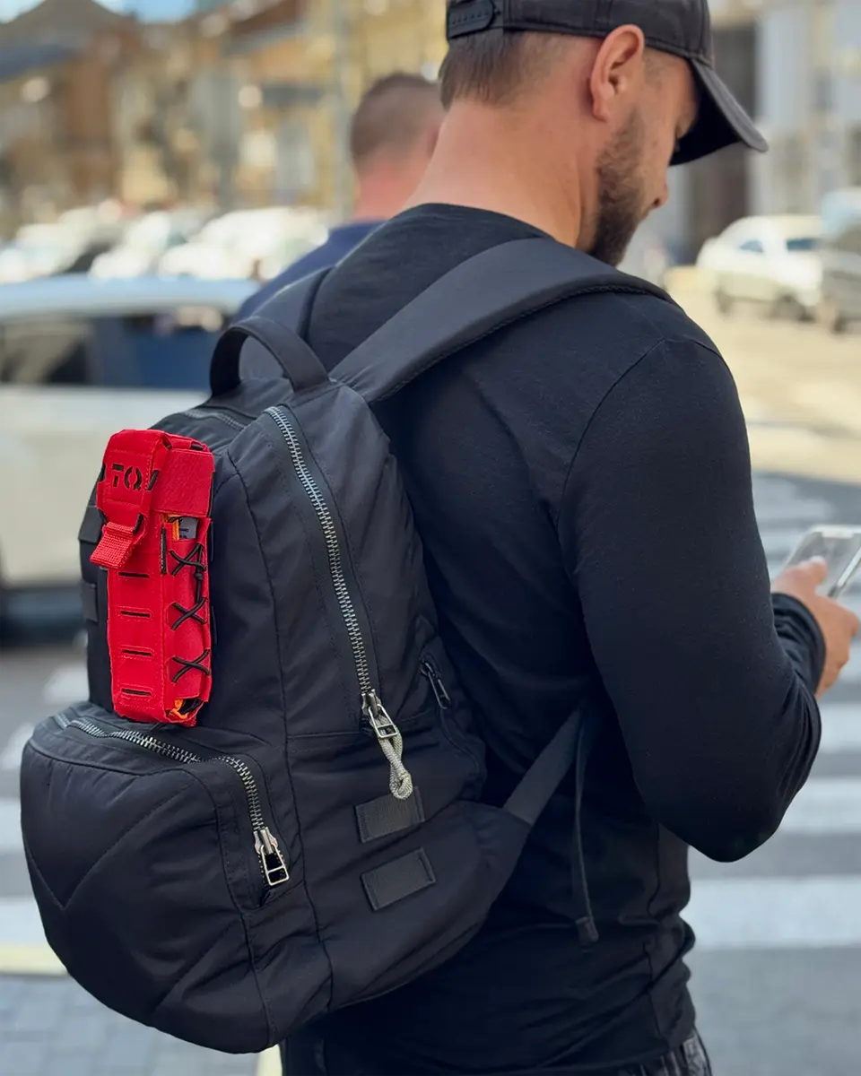 Porta tourniquet tattico DNIPRO Gen2 PM03 rosso montato sul retro di uno zaino durante l'utilizzo