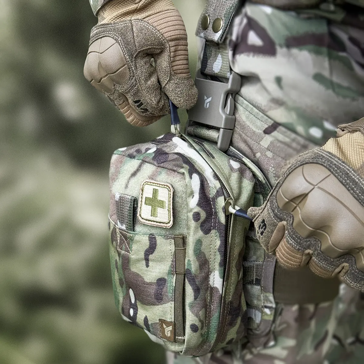 Mani con guanti tattici che aprono la zip YKK della tasca cosciale medica DNIPRO PM21 Multicam per l'estrazione rapida del materiale sanitario.