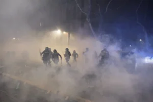 fotoreporter-sicurezza-manifestazioni-16 Persone in movimento nella strada avvolta dal fumo dei lacrimogeni