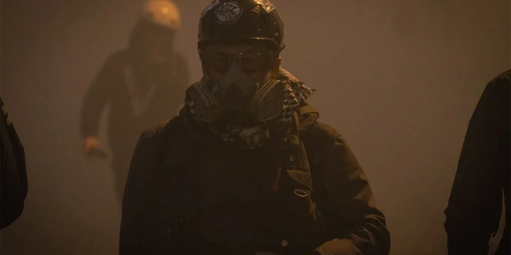 Fotoreporter con casco e maschera antigas durante una manifestazione