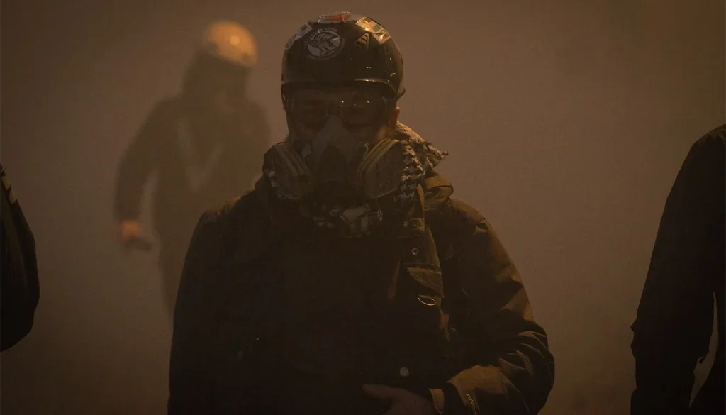 Fotoreporter con casco e maschera antigas durante una manifestazione